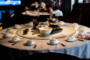 A round restaurant table set with a lazy Susan, teapot and cups