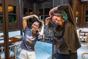 Two people make a heart shape with their arms in a restaurant