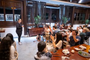Diners applaud a woman standing to speak in a restaurant hall