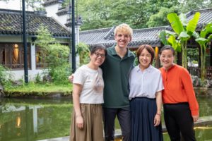 Four friends pose by a pond in a traditional garden