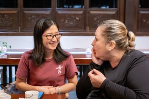 Two women chat and smile at a dinner table