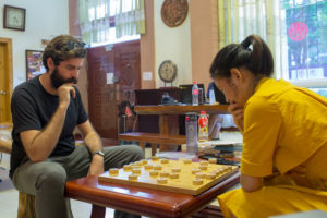 Two people concentrate on a Chinese chess game at a small table