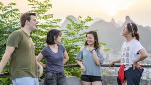 Four friends chat and smile at a mountain viewpoint