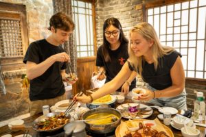 Friends serve themselves from a hot pot dinner in a rustic dining room