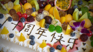 A fruit-covered anniversary cake with Chinese characters in icing