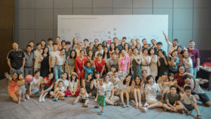 A large crowd poses in front of a white signing wall at an event