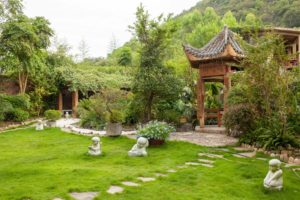 A quiet garden courtyard with a lawn, stone path and small pavilion