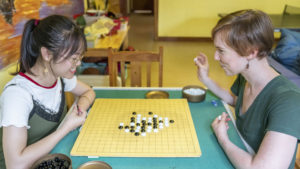 Two women lean over a Go board and study the game