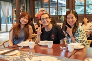 Three people smile toward the camera at a restaurant table