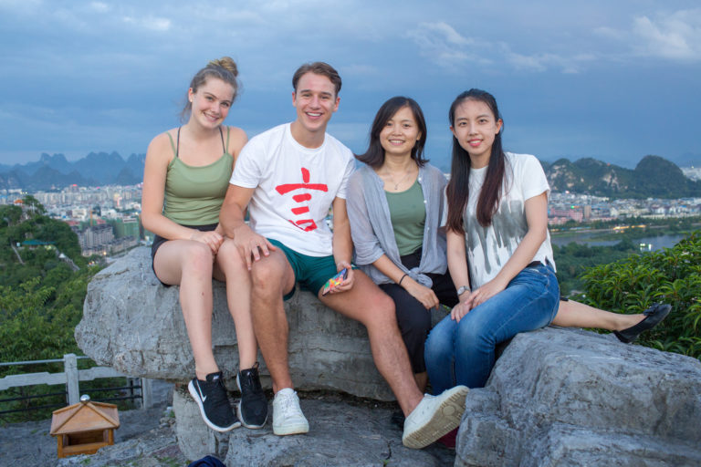 Quatre amis assis sur un rocher bien au-dessus de la ville