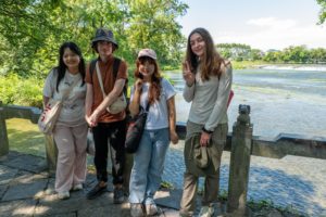 Four friends pose on a stone path beside a river