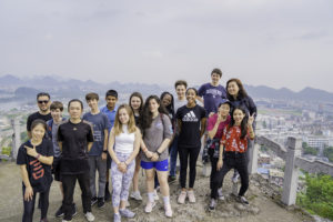 A large group poses on a mountain overlook above the city