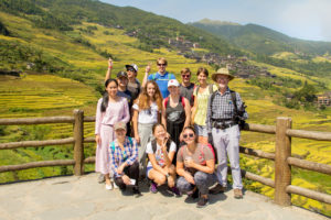 A group poses at a scenic overlook above terraced hillsides