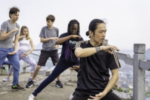 A small group practices tai chi on a hilltop overlook