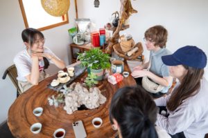 People gather around a round wooden table for a tea session