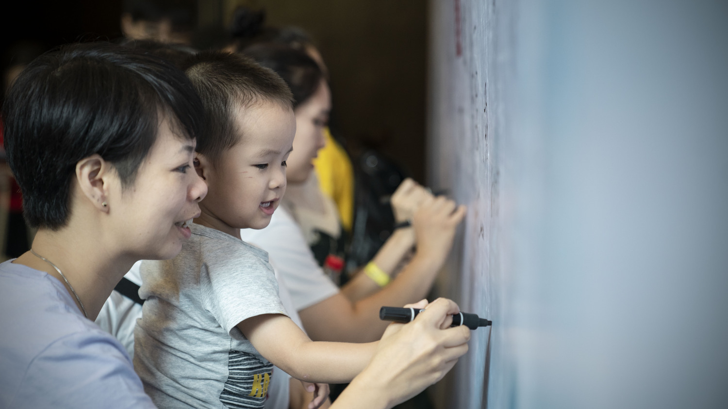 Guests writing messages on the signature wall at the CLI Center