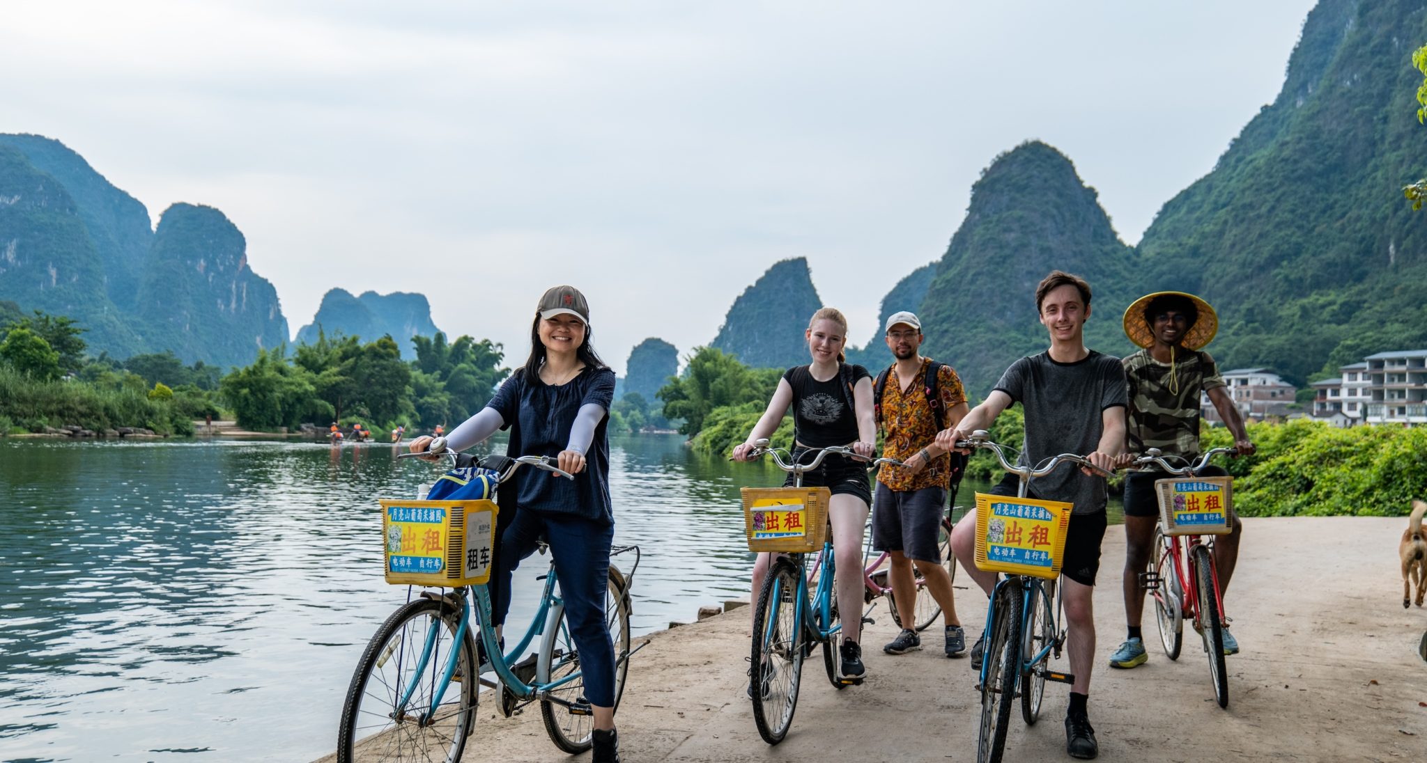 Adult CLI students and a team member cycling beside the karst mountains near Guilin