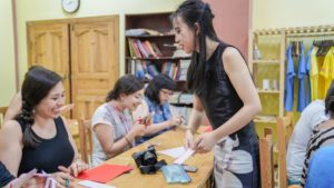 A paper-cutting instructor helps seated students during a craft lesson
