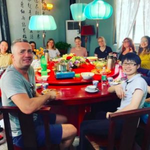 Friends smile around a round dinner table with a red lazy Susan