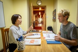 A teacher and student talk across a desk with books