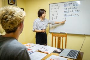 A teacher points to Chinese characters on a whiteboard during a lesson