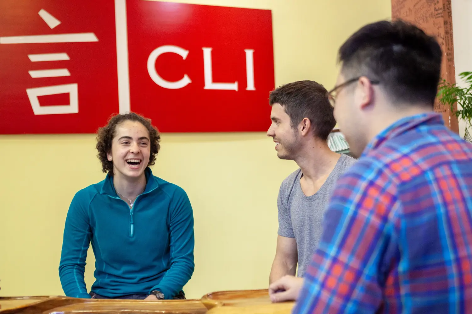 CLI students and staff sharing a warm conversation beneath the CLI sign
