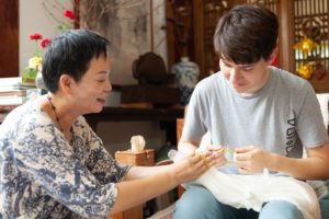 An instructor shows a student how to stitch fabric for tie-dye