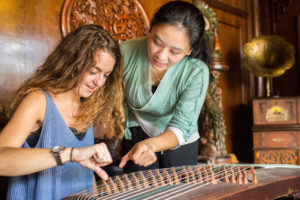 An instructor points out the strings as a student plays guzheng
