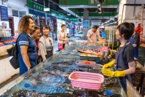 Students look over tanks at a seafood stall in an indoor market