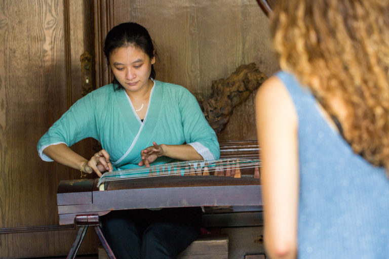 Une femme jouant du guzheng pendant qu'une personne regarde