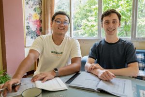 A teacher and student smile at a table with open textbooks