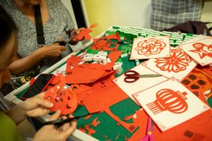 Red paper-cut designs and scissors spread across a workshop table