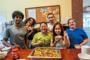 A cooking group smiles behind a finished dish