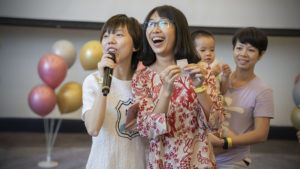 A woman with a microphone stands by as another laughs over a prize slip