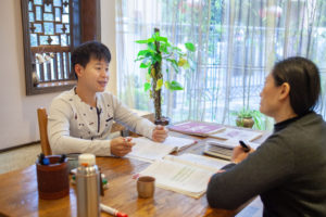 A teacher and student work through a lesson at a wooden table