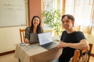 A student and teacher smile at a table with laptops
