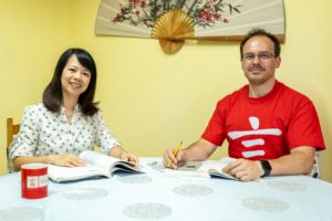 A smiling teacher and a student in a red CLI shirt at a table