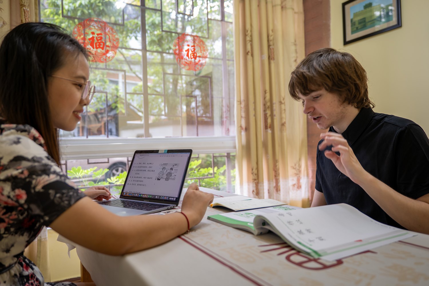 Student and teacher studying Chinese together by a classroom window