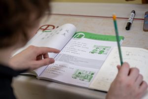A student points a pencil at a Chinese textbook page