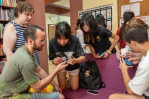 People gather around a lounge couch and look at their phones
