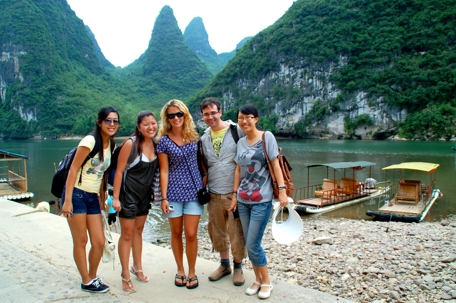 Students along a river with karst mountains in the background in Guilin