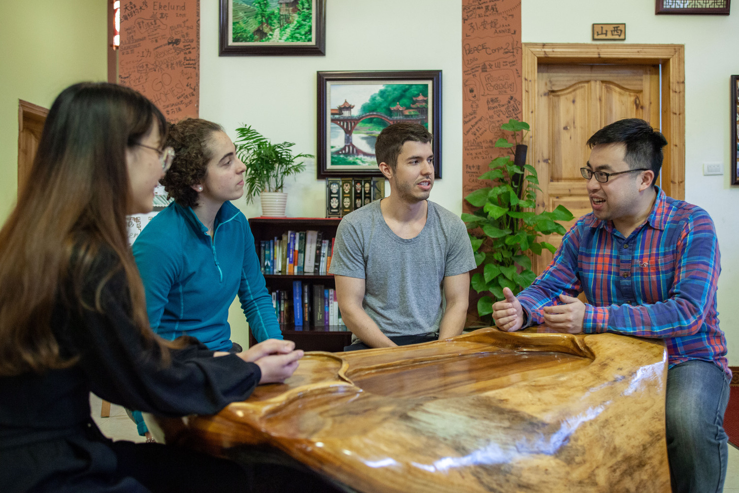 Three people in conversation around a wooden table at the CLI center in Guilin