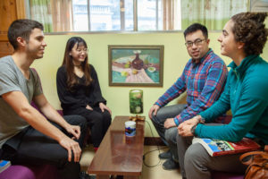 Four people sit and chat in a small lounge