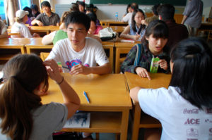 Students work in small groups at wooden desks in a classroom