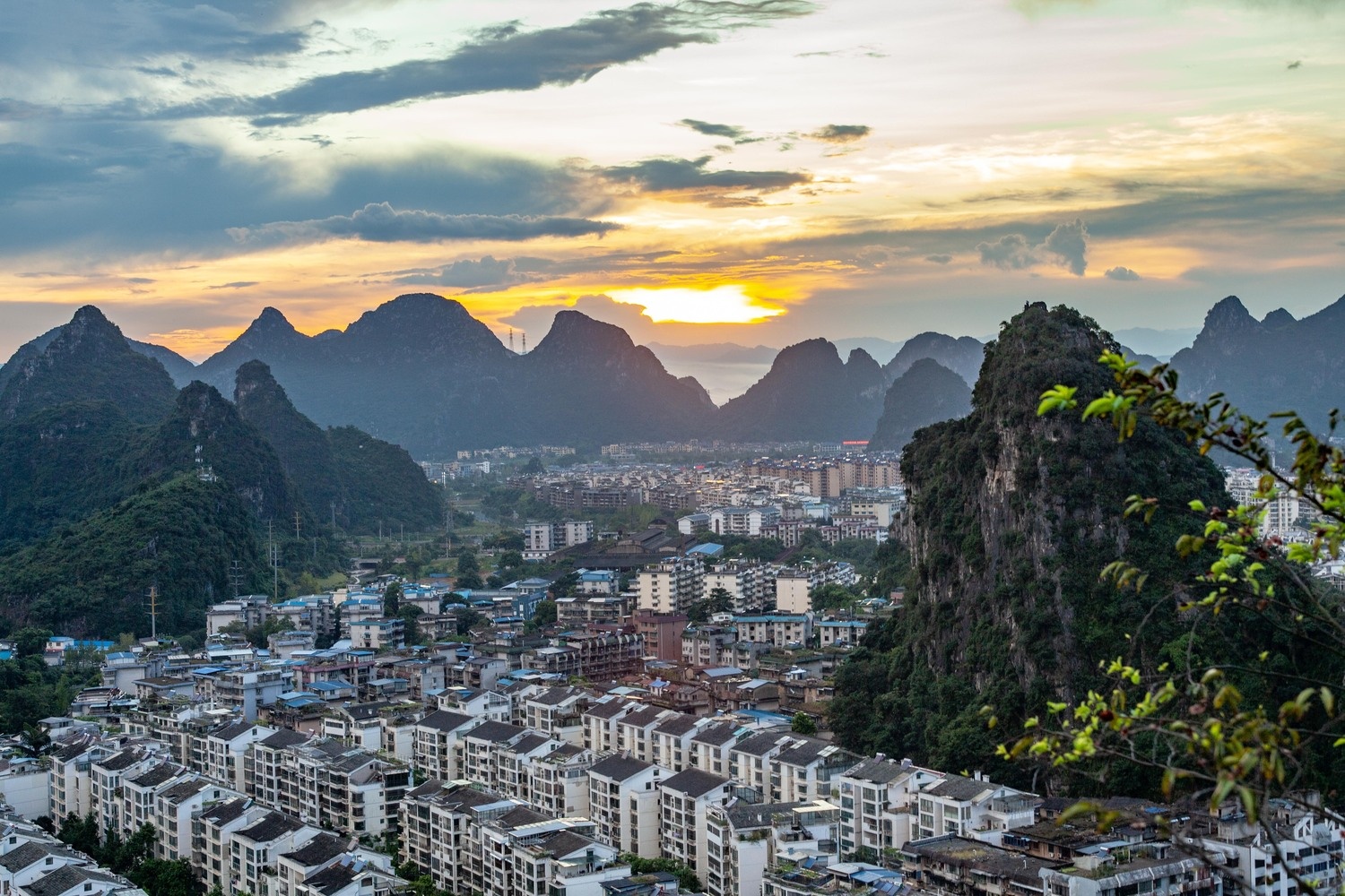 Sunset over a cityscape with karst mountains in the background