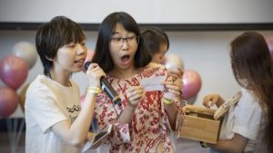 A surprised woman reads a prize slip as another holds the microphone