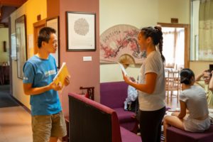 A teacher and student talk over a book in the Center lounge
