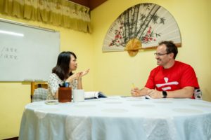 A teacher and student talk across a round table during a lesson