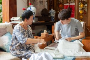 An instructor shows a student how to prepare cloth for tie-dye
