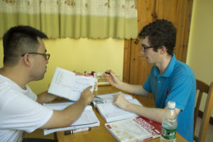 A teacher and student review a notebook together across a table